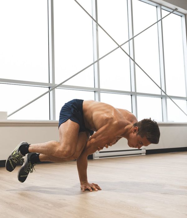 A strong man performing balance exercises in a dark gym environment.